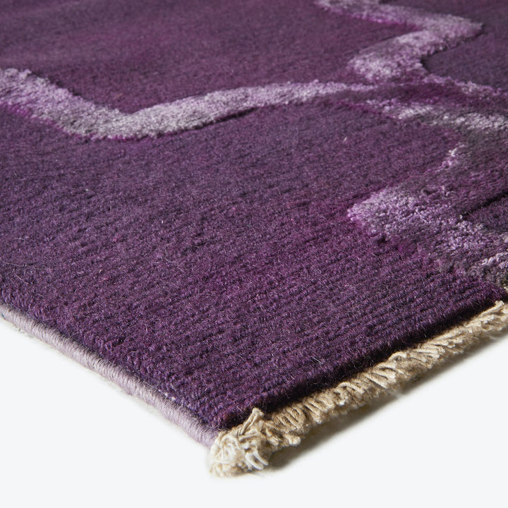 Close-up of a plush purple rug with geometric design.
