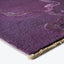 Close-up of plush, purple-hued rug with abstract, textured design.