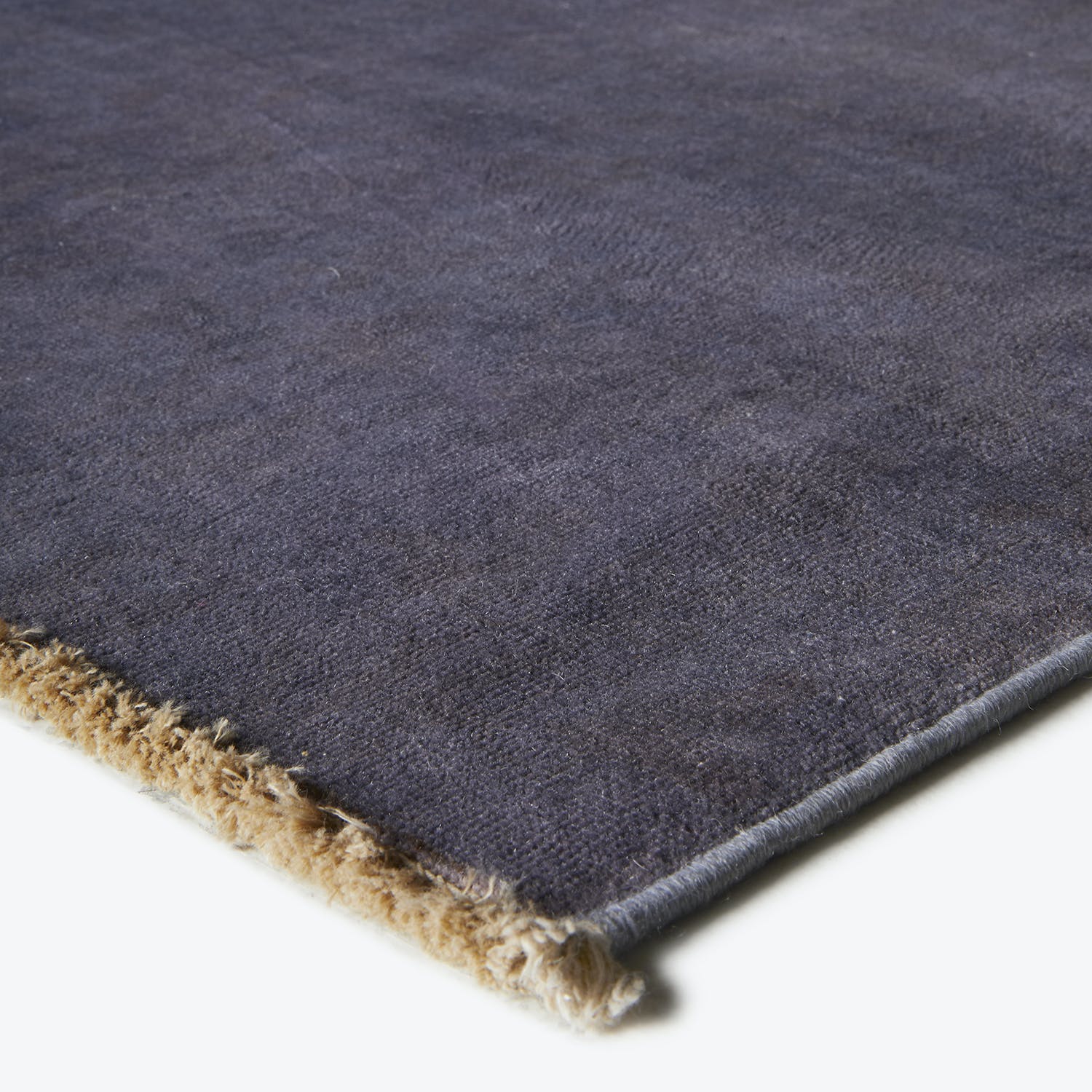 Close-up of a plush navy rug with contrasting beige finishing.
