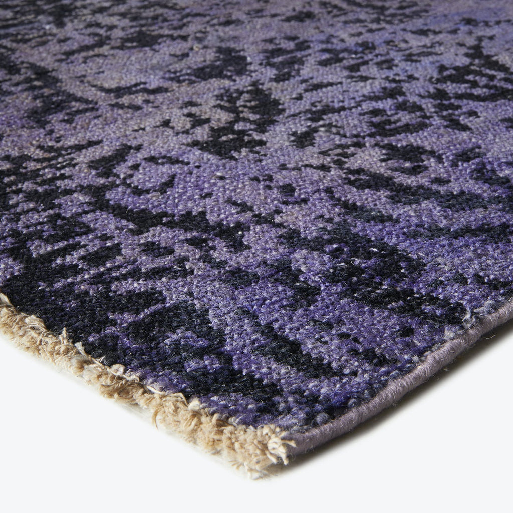 Detailed close-up of a plush purple rug with abstract design.