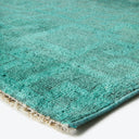 Close-up of a teal or turquoise plush carpet, with varying shades and neat edges.