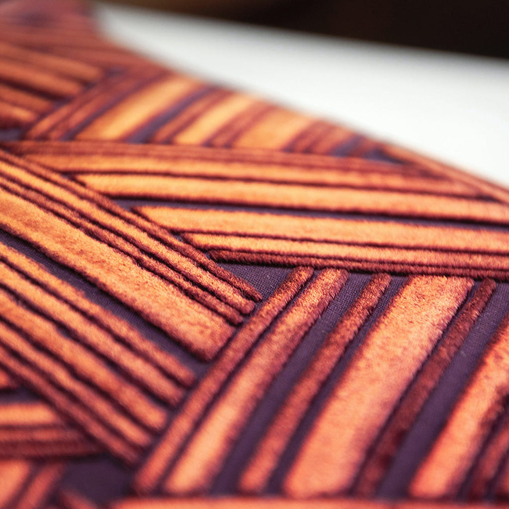 Close-up of a textured fabric with orange and dark purple stripes, creating a zigzag pattern.