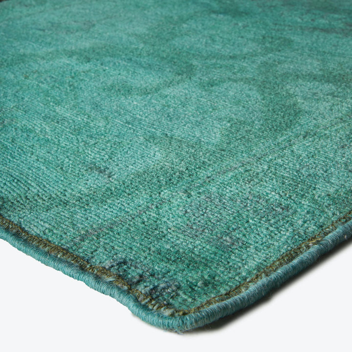 Close-up of a teal textured rug with plush, dense pile.