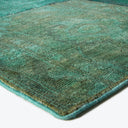 Close-up of vintage green rug with textured surface and abstract pattern.