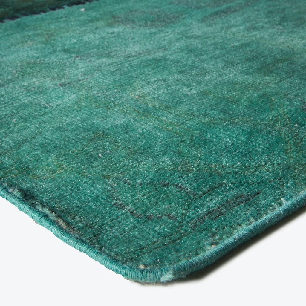 Close-up of a worn teal rug with textured surface.