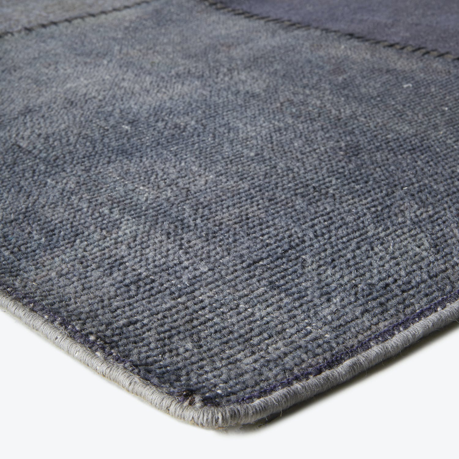 Close-up of a gradient fabric rug with tight construction and hemmed edges.