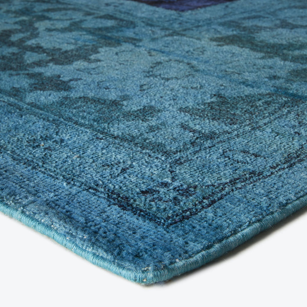 Close-up of vintage-style blue carpet with textured, faded pattern.