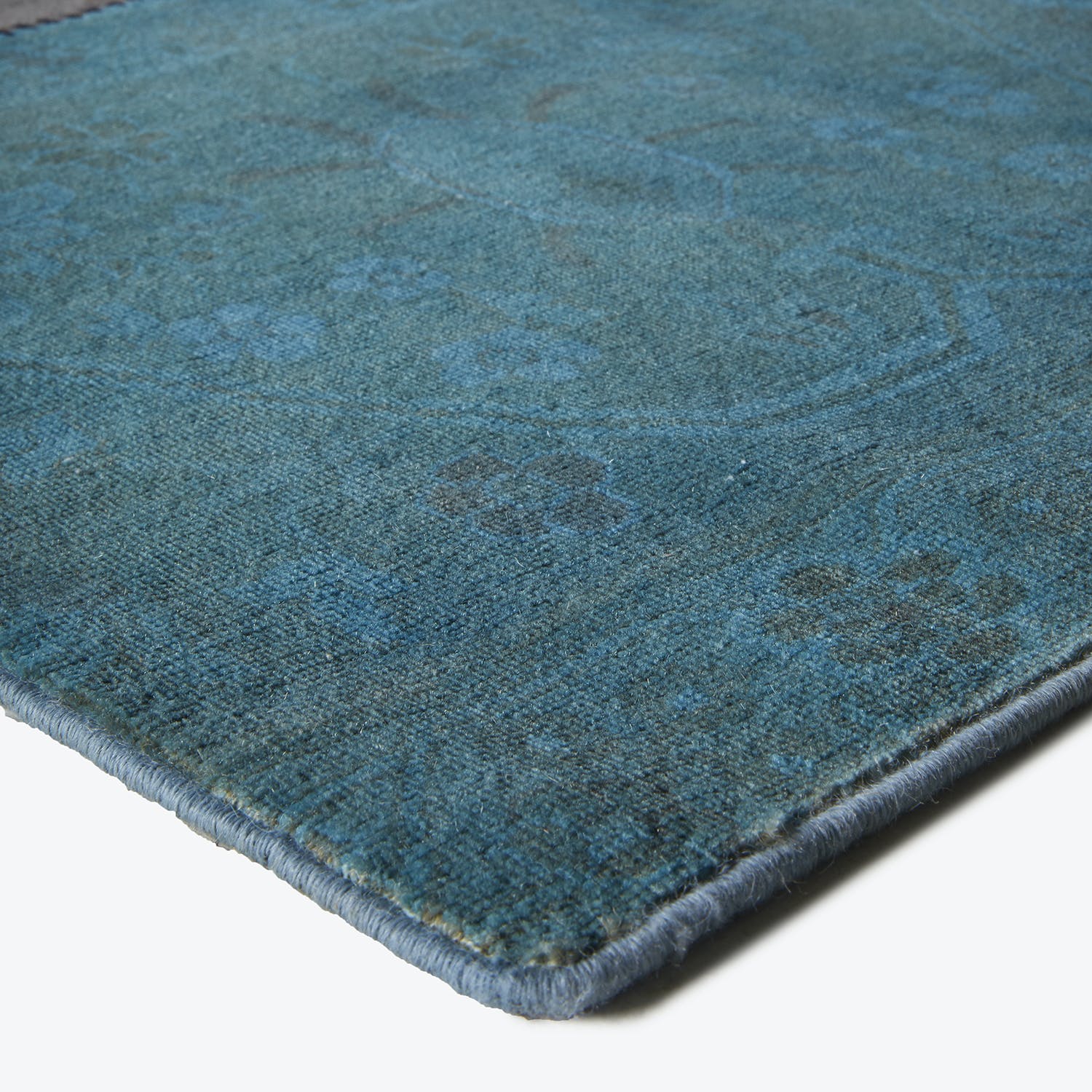 Close-up of a high-quality teal carpet with intricate patterns.