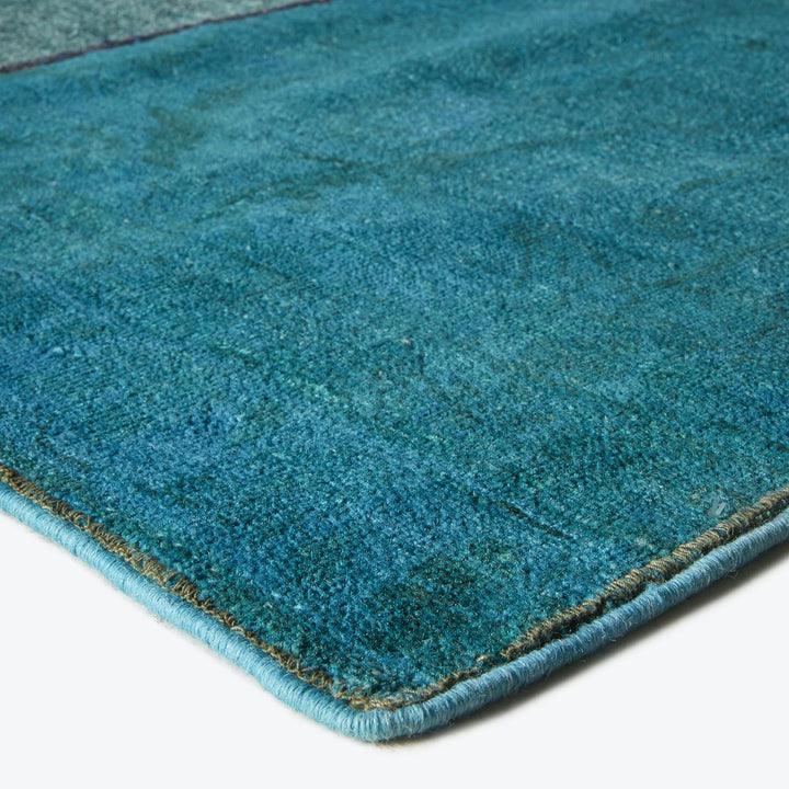Close-up of teal carpet with plush texture and neat trim.