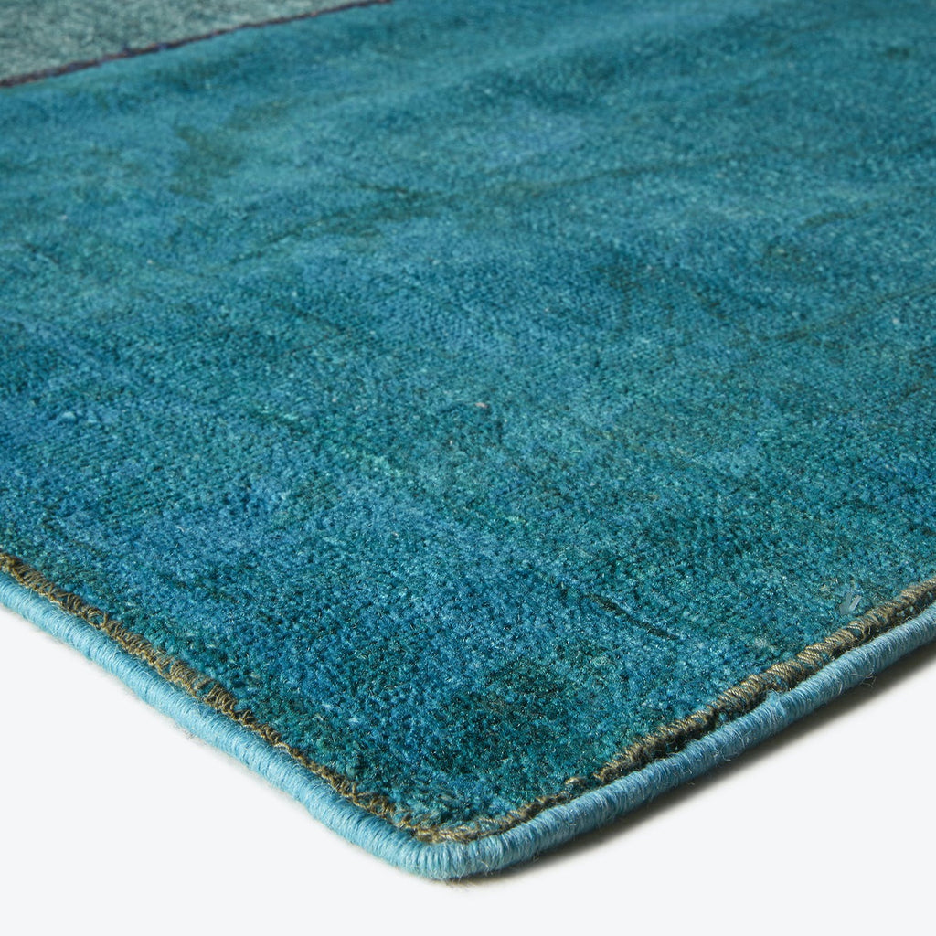 Close-up of teal carpet with plush texture and neat trim.