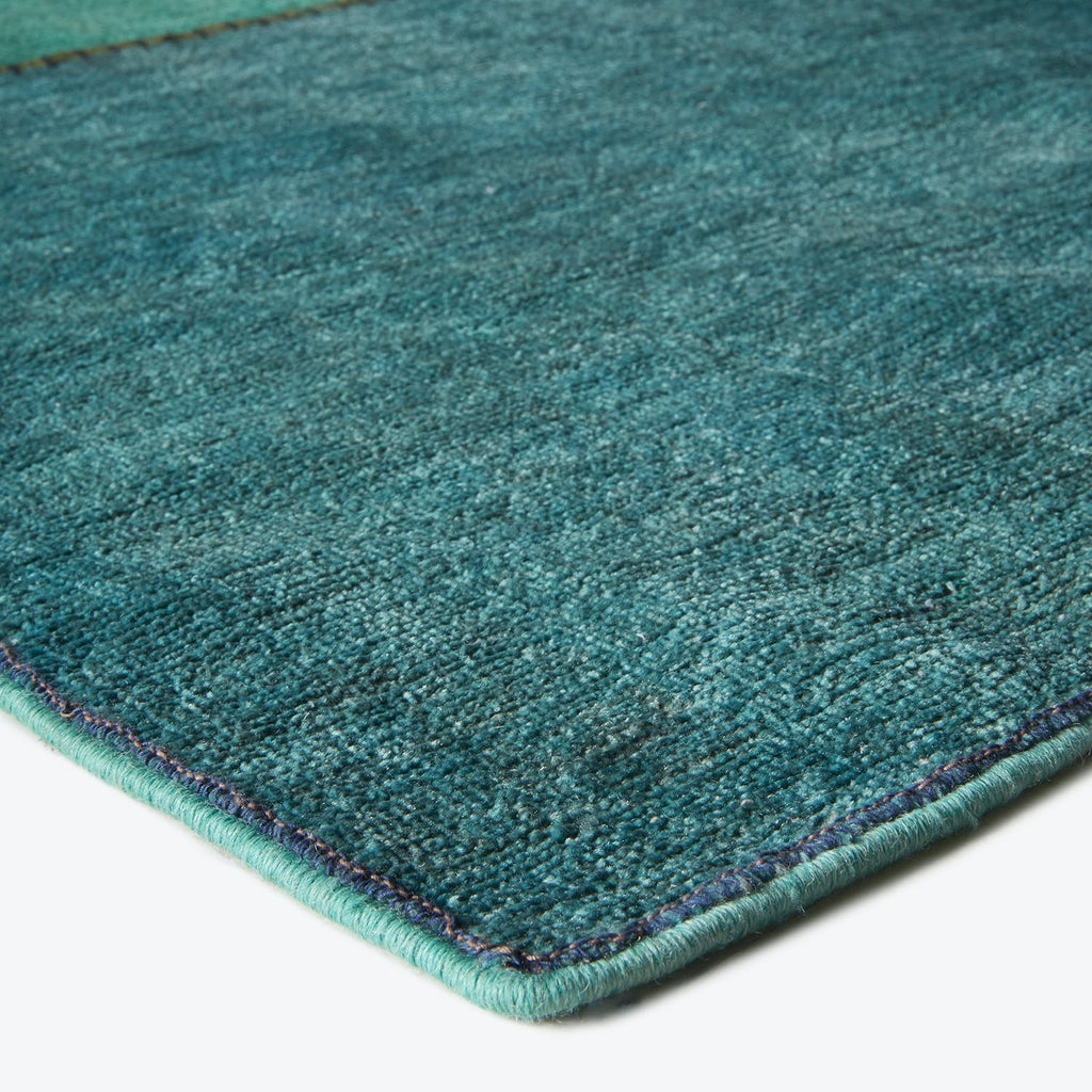 Vibrant teal rug with plush texture and elegant binding detail.