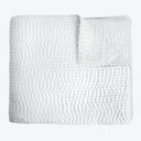 Stylish and cozy, a textured white quilted bedspread or blanket.