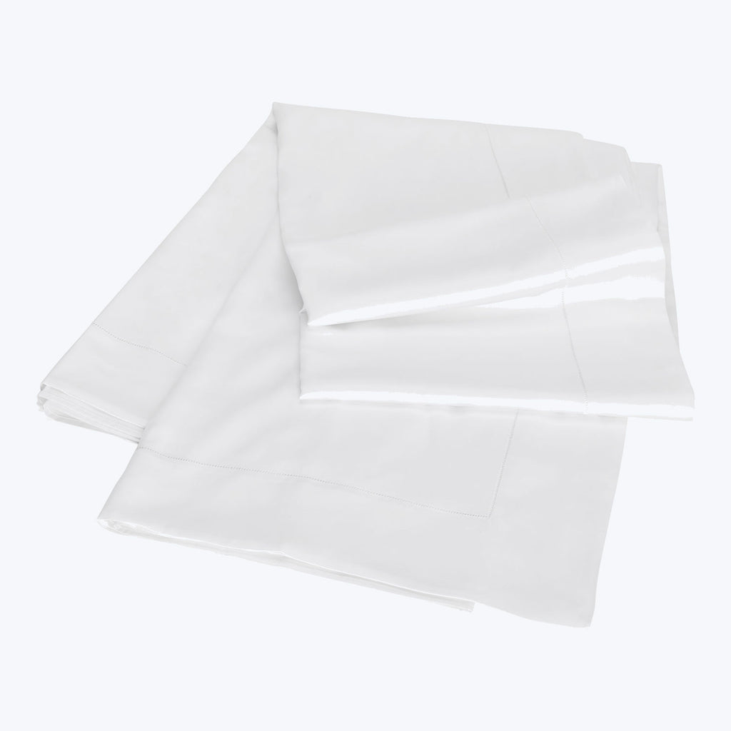 Simple and versatile white bed linens neatly folded and soft.