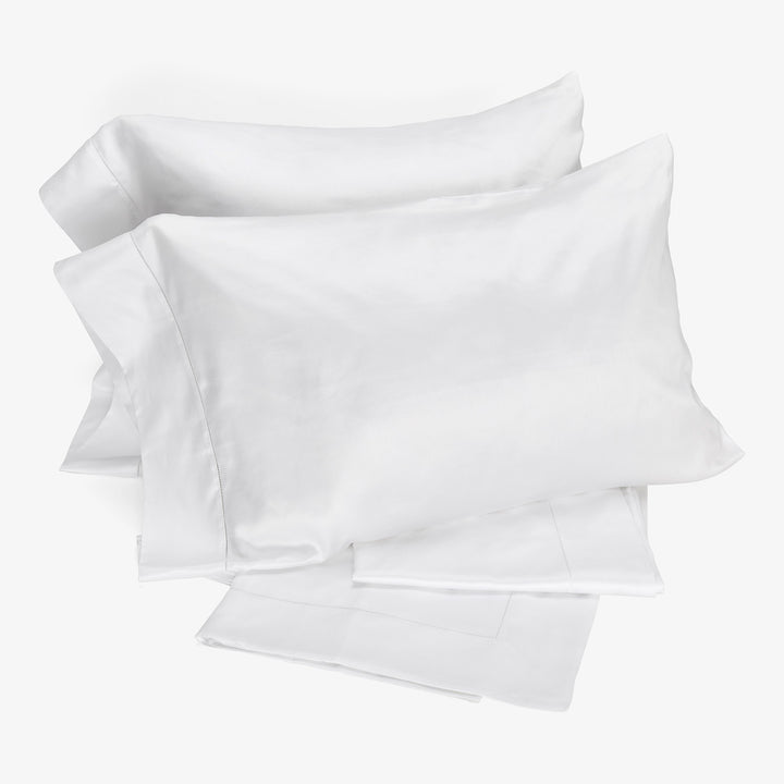 Three soft, cotton pillowcases neatly stacked, offering versatile bedding options.