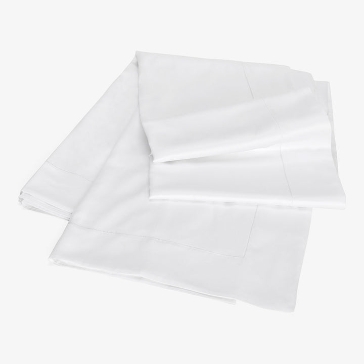 Neatly folded white pillowcases with elegant stitched borders on display.