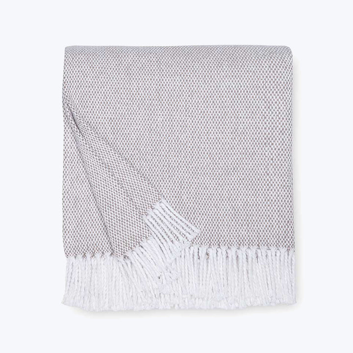 Neatly folded herringbone throw blanket with white tassel fringe.