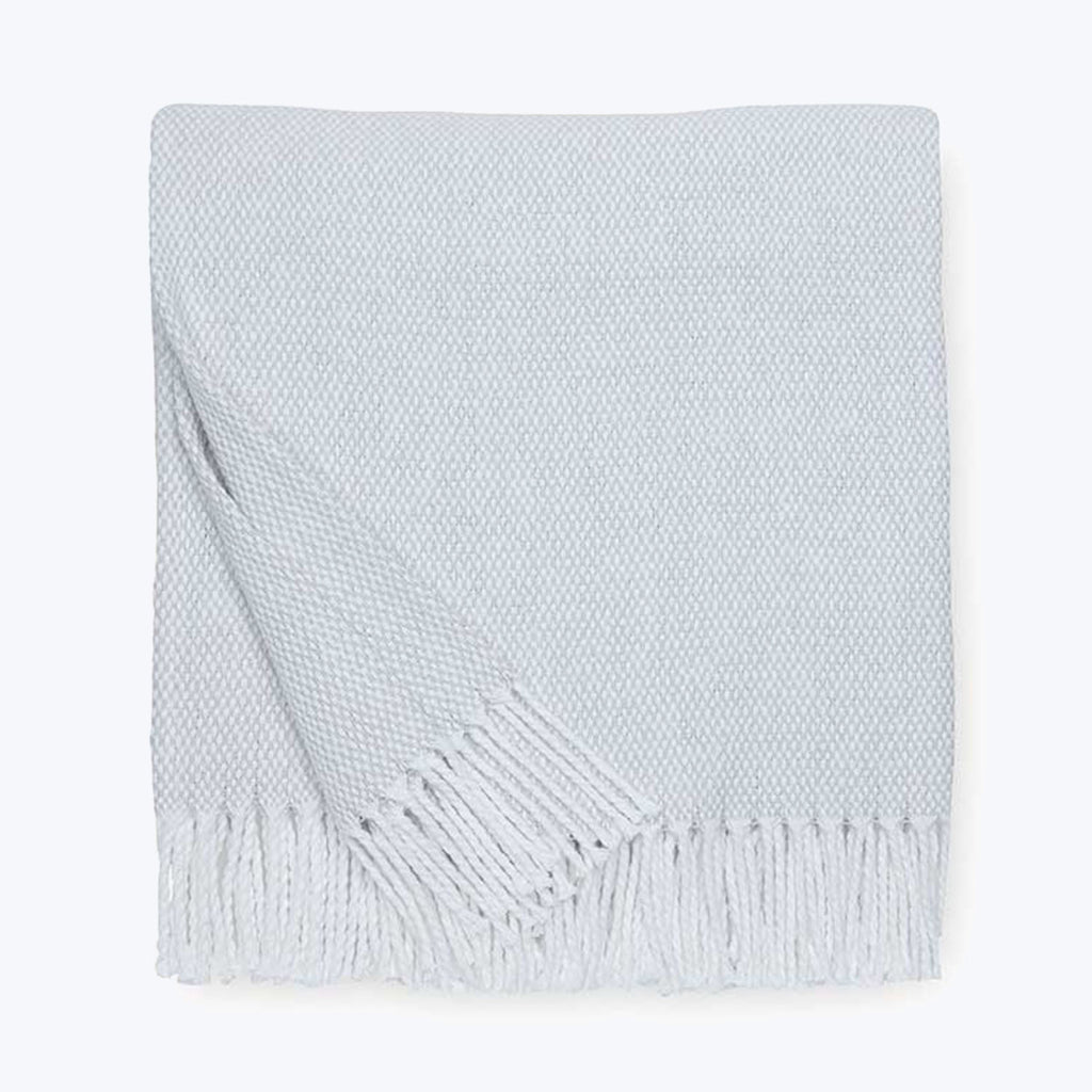 Light gray knit throw blanket with fringed edges, showcasing texture.