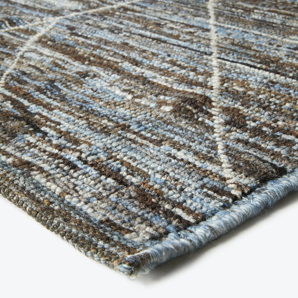 Close-up of a textured rug with intersecting lines and frayed binding
