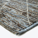 Close-up of a textured rug with intersecting lines and frayed binding
