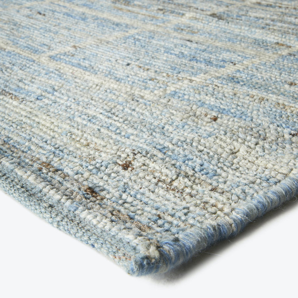 Close-up view of a high-quality, blue textured rug with beige specks.