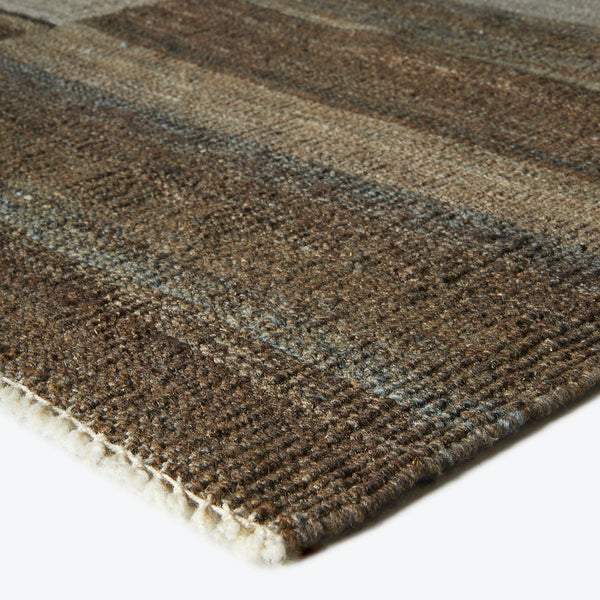 Close-up of a textured rug with horizontal stripes in earthy tones.