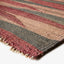Close-up of a colorful, textured striped rug with tassels.