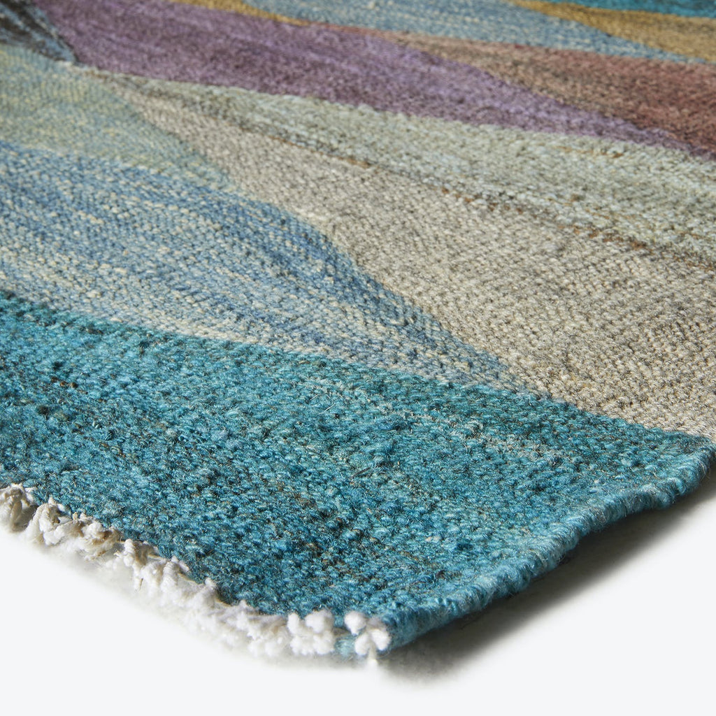 Vibrant gradient rug with textured appearance and white fringed edge