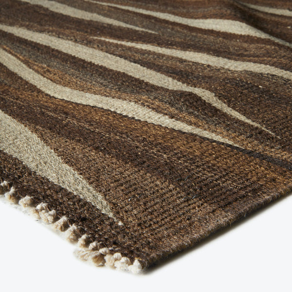 Close-up of a handwoven, striped rug with earthy tones and fringe.