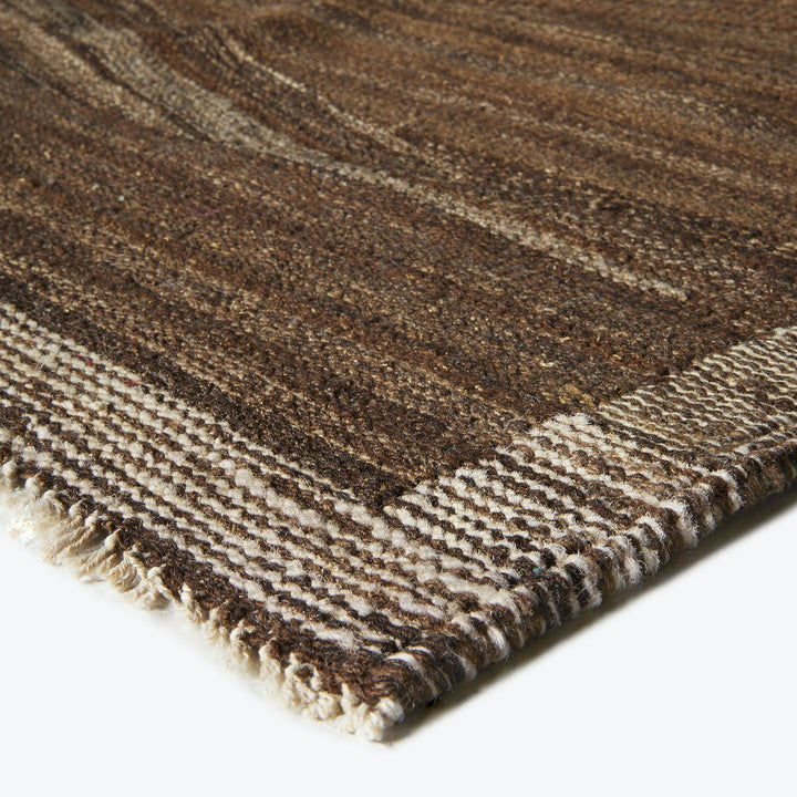 Textured brown rug with gradient tones and fringe detail visible.
