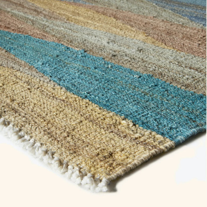 Close-up view of a colorful and textured striped rug with fringe.