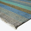 Striped textile with shades of blue and green, fringe detail.