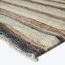 Close-up of a thick, handwoven striped rug with earthy tones.