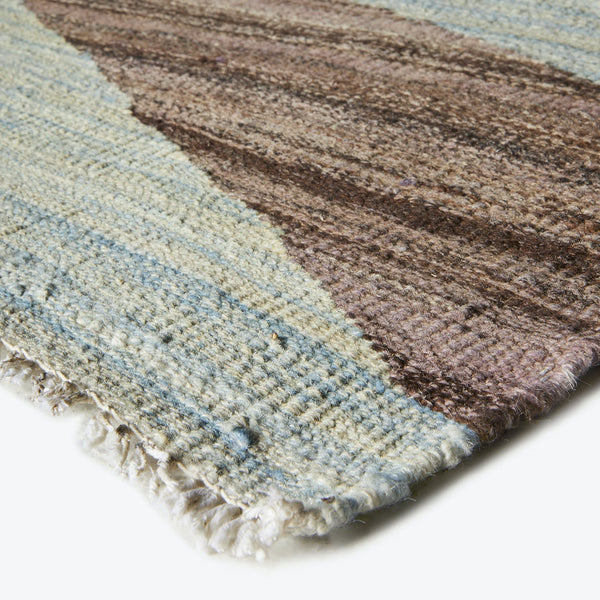 Close-up view of a striped rug with soft texture and fringe.