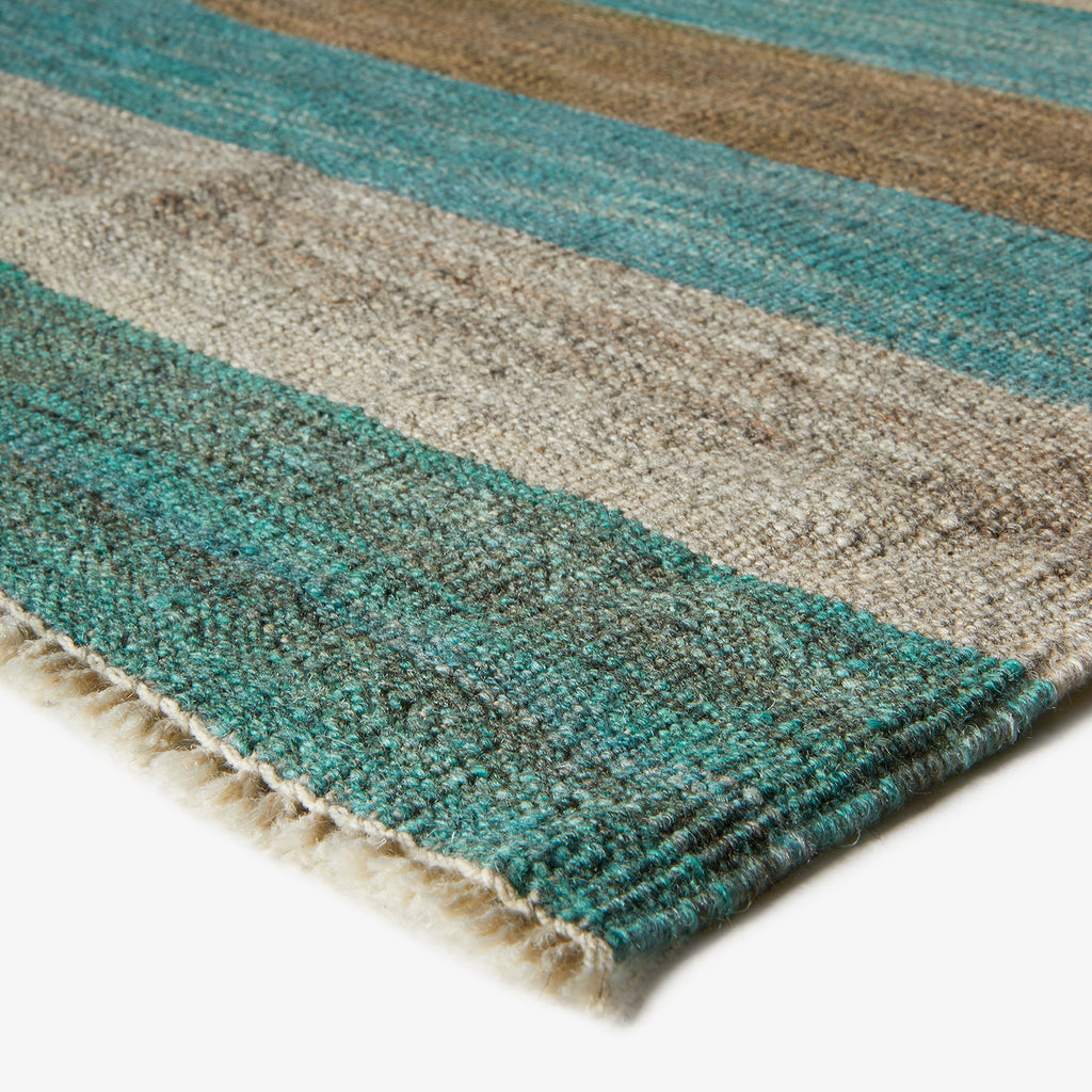 Close-up of textured fabric with alternating blue, green, and tan stripes.