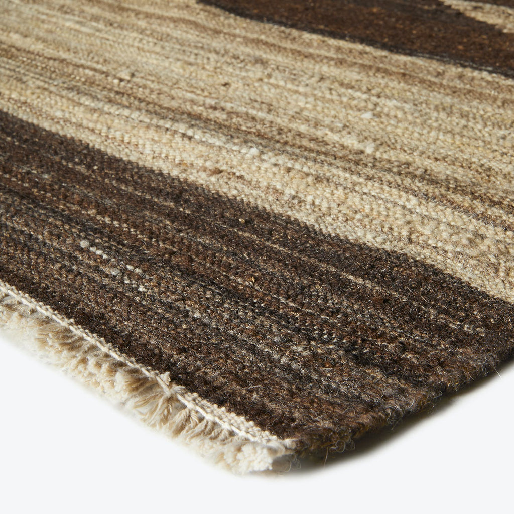 Close-up of a textured rug with alternating brown, beige, and cream stripes.