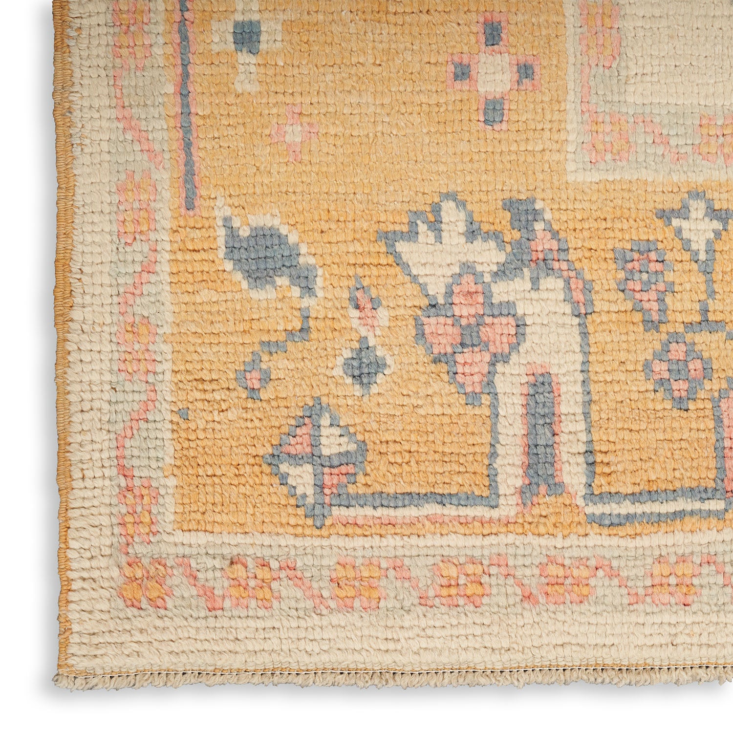 Close-up of a hand-woven floral rug with muted colors.