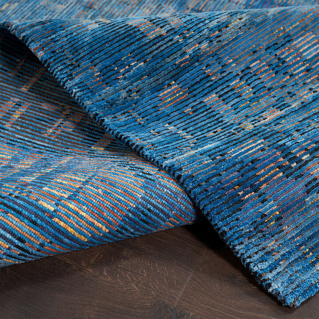 Close-up of vibrant, handwoven rug on dark wood flooring.