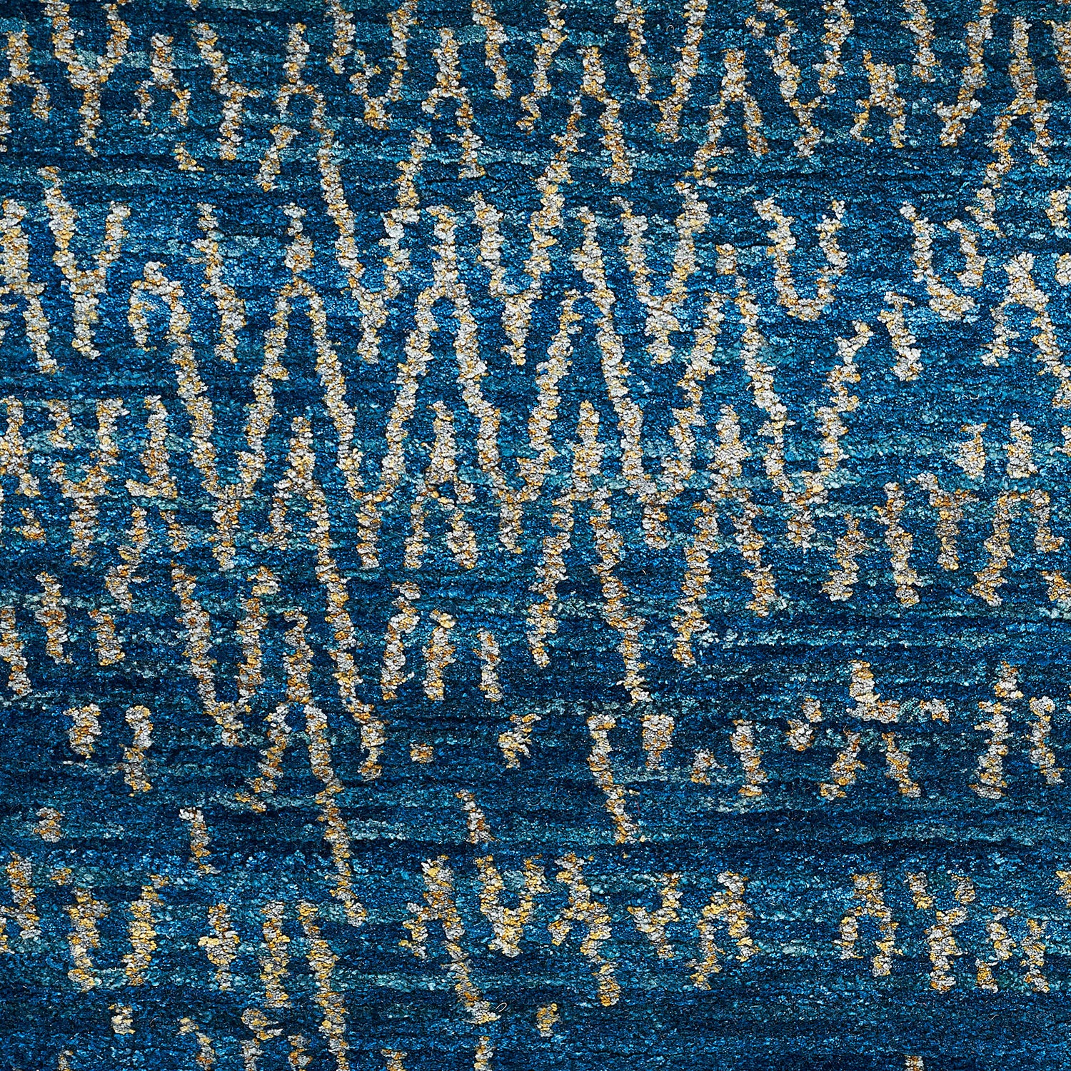 Rich blue fabric with golden streaks creates luxurious, ornamental texture.