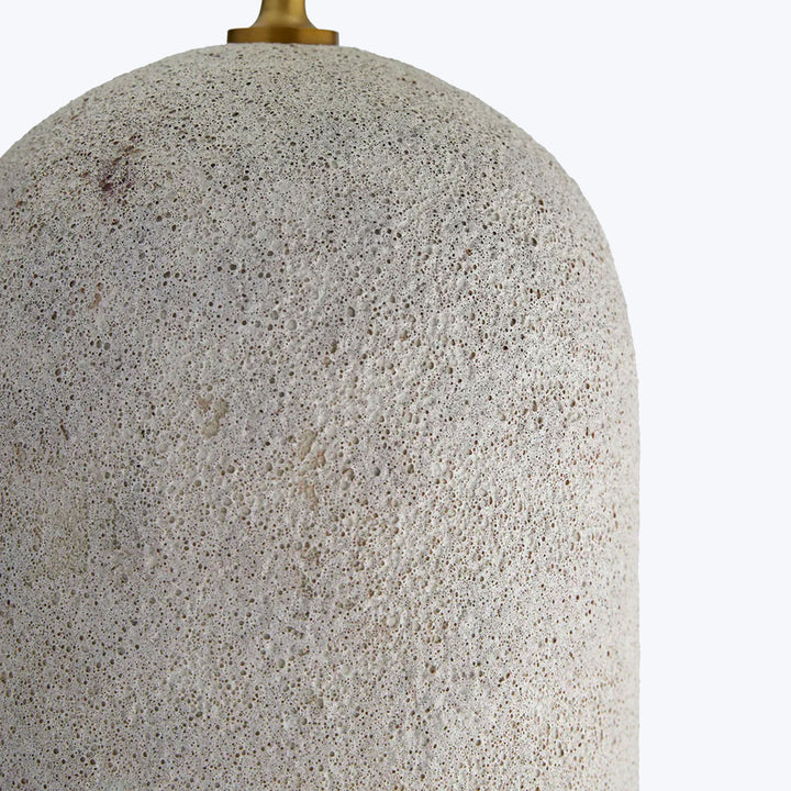 Close-up of porous, speckled textured surface with brass/gold element.