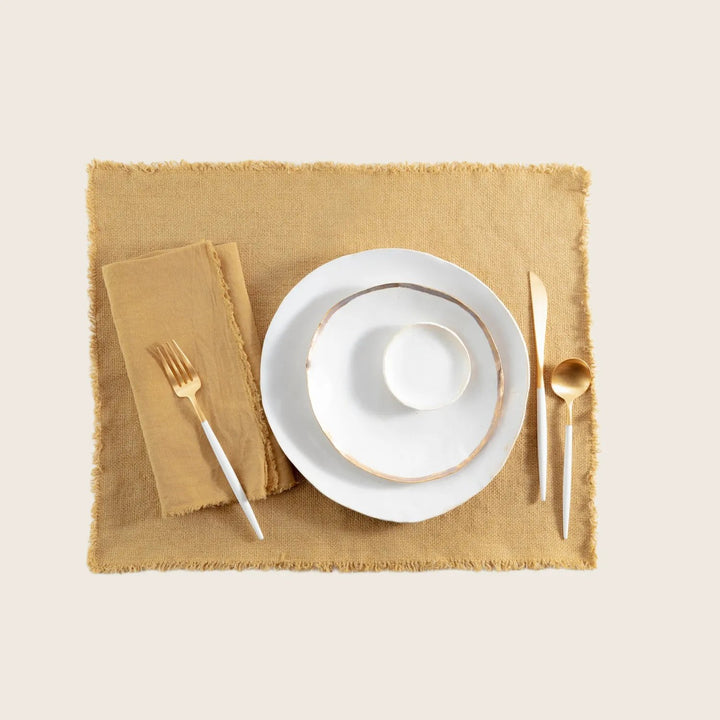 Elegant and rustic table setting with gold accents on white background.