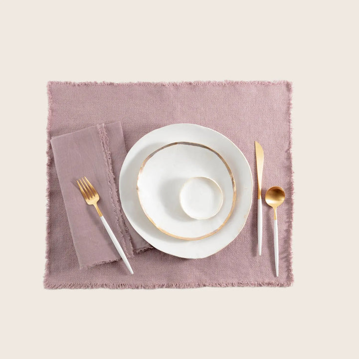 Elegant minimalist table setting with gold-rimmed dinnerware and matching flatware.