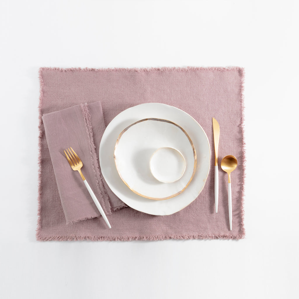 Elegant minimalist table setting with gold-rimmed dinnerware and matching flatware.