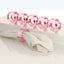 Elegant pink crystal napkin rings sparkle on a reflective surface.