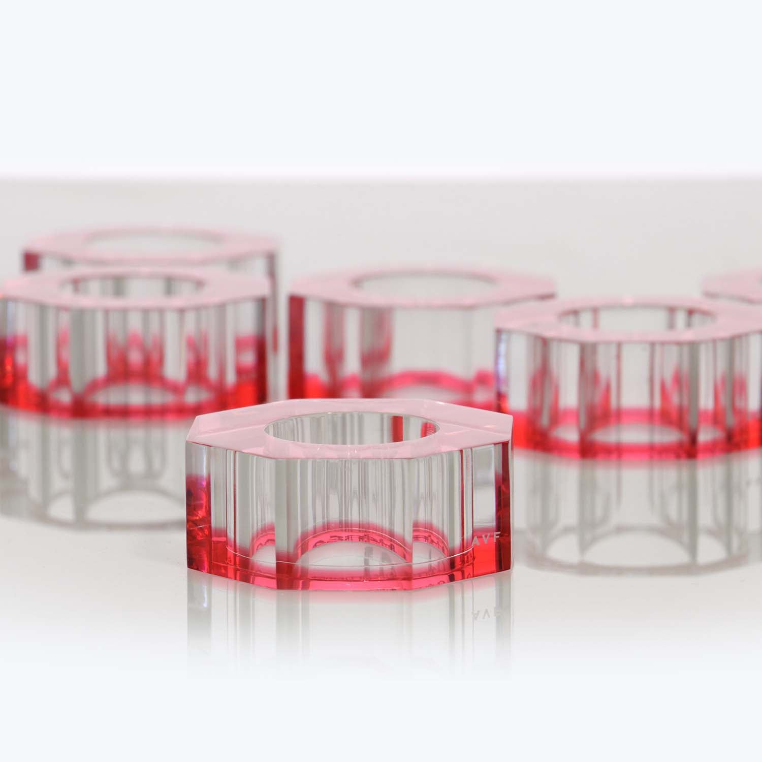 Transparent cylindrical objects with pink-red hue reflect light on surface.