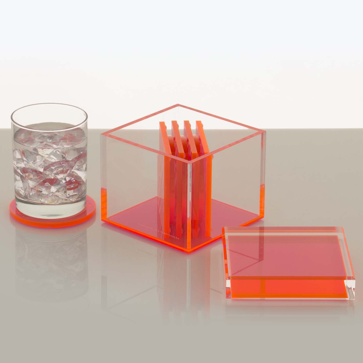 Minimalistic orange-themed items: glass tumbler with ice and open cigarette box.