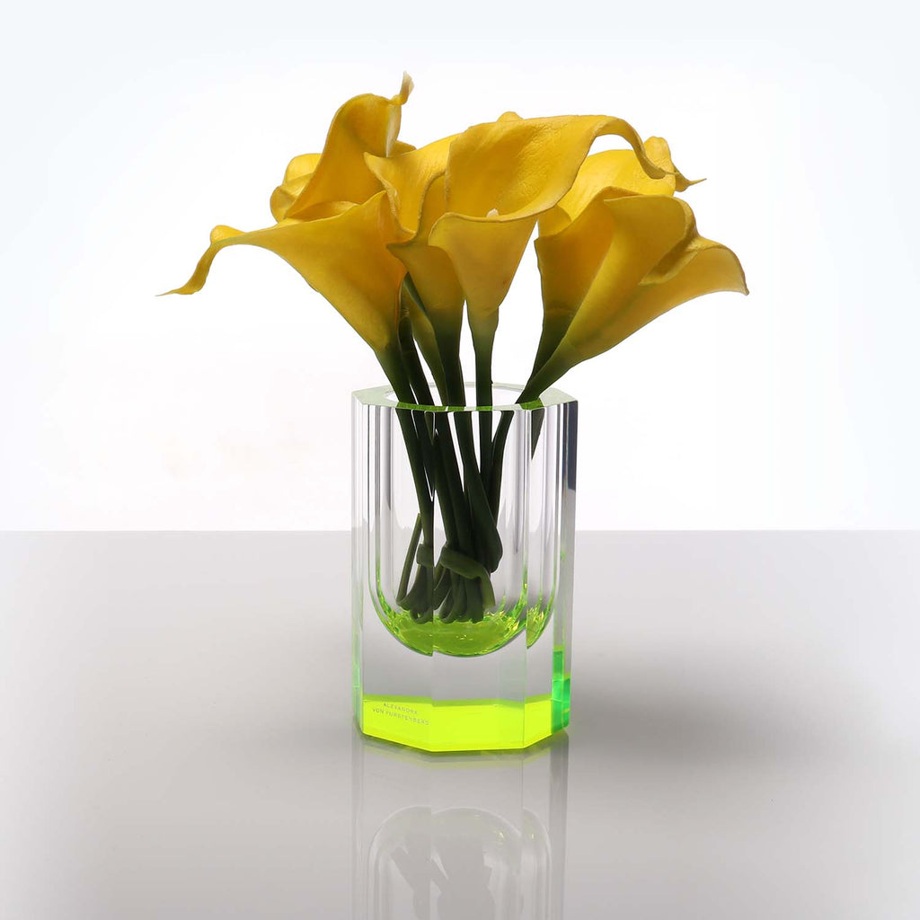 Vibrant yellow calla lilies stand tall in modern glass vase.