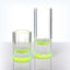 Contemporary glass tumblers with a vibrant green base on reflective surface