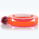 Vibrant pink acrylic bowl with reflective surface and floral accent.