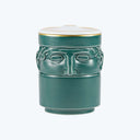 Cylindrical teal container with stylized human face relief decoration.