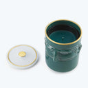 Decorative dark green candle with embossed design and glossy finish.